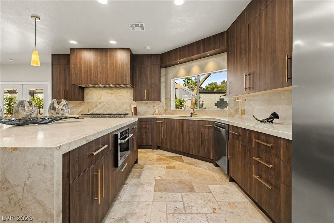 Rich wood cabinetry contrasts beautifully with light stone countertops and matching tiled flooring.