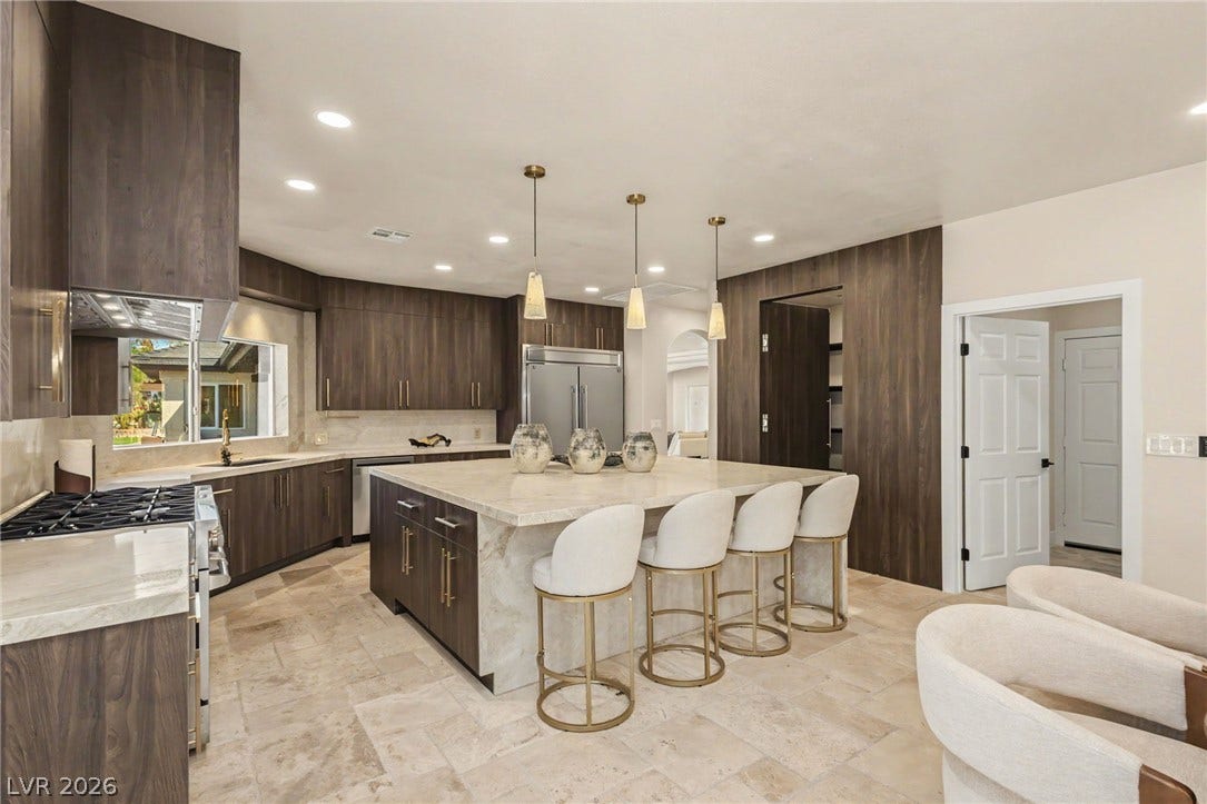 Rich wood cabinetry contrasts with light stone countertops in this open culinary space.