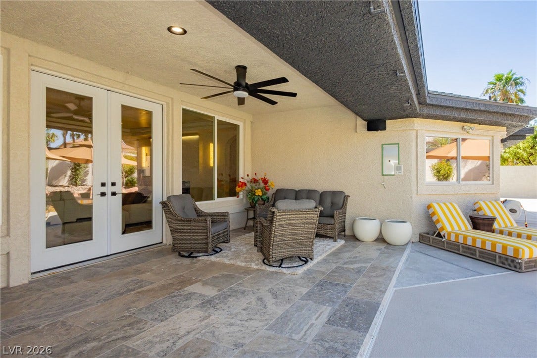 A spacious covered patio features tiled flooring and glass-paneled french doors.