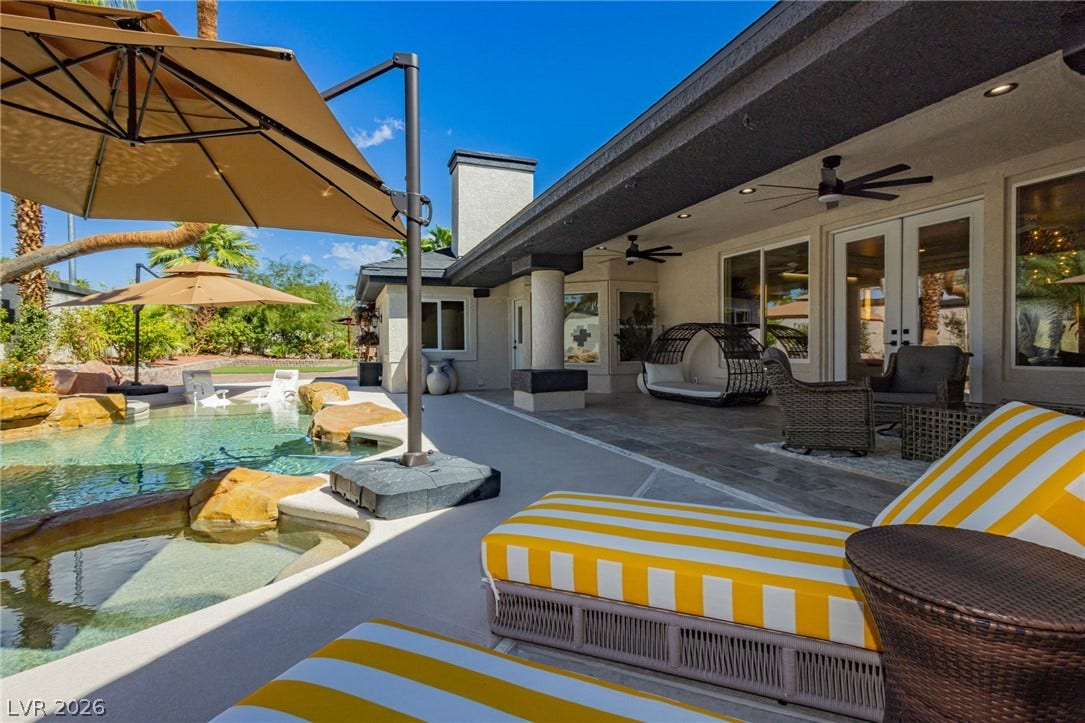 An inviting backyard oasis features a custom swimming pool alongside a spacious covered patio.