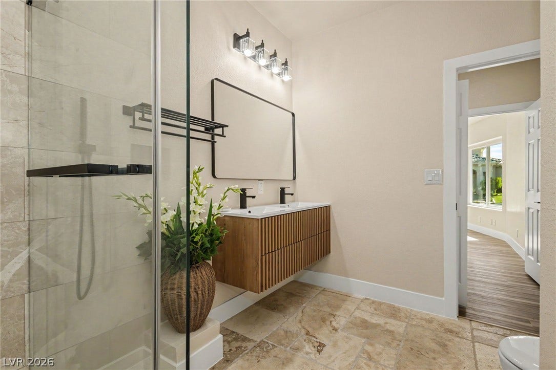 Natural stone tile floors and a sleek floating vanity elevate this modern bathroom design.