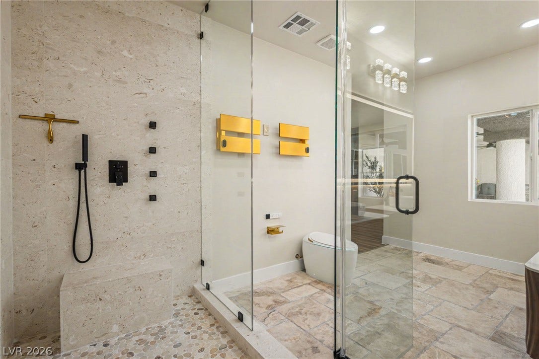 Stone tile floors and a glass-enclosed walk-in shower anchor this contemporary bathroom.