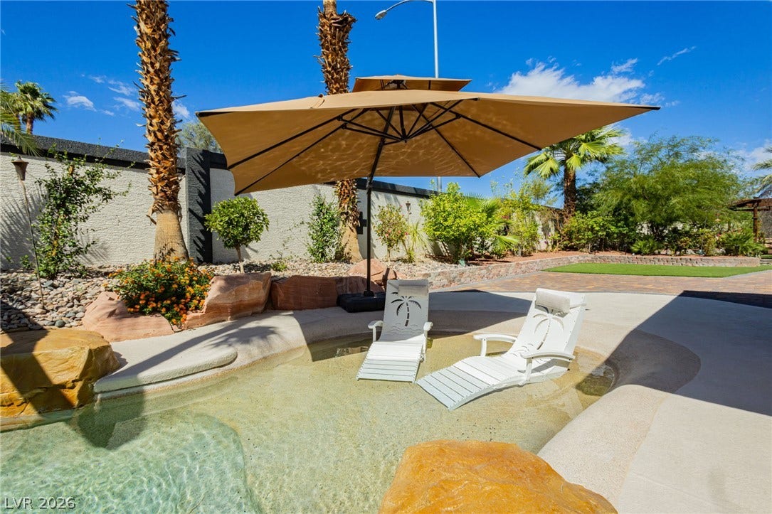 An inviting shallow pool ledge provides a relaxing oasis framed by mature palm trees.