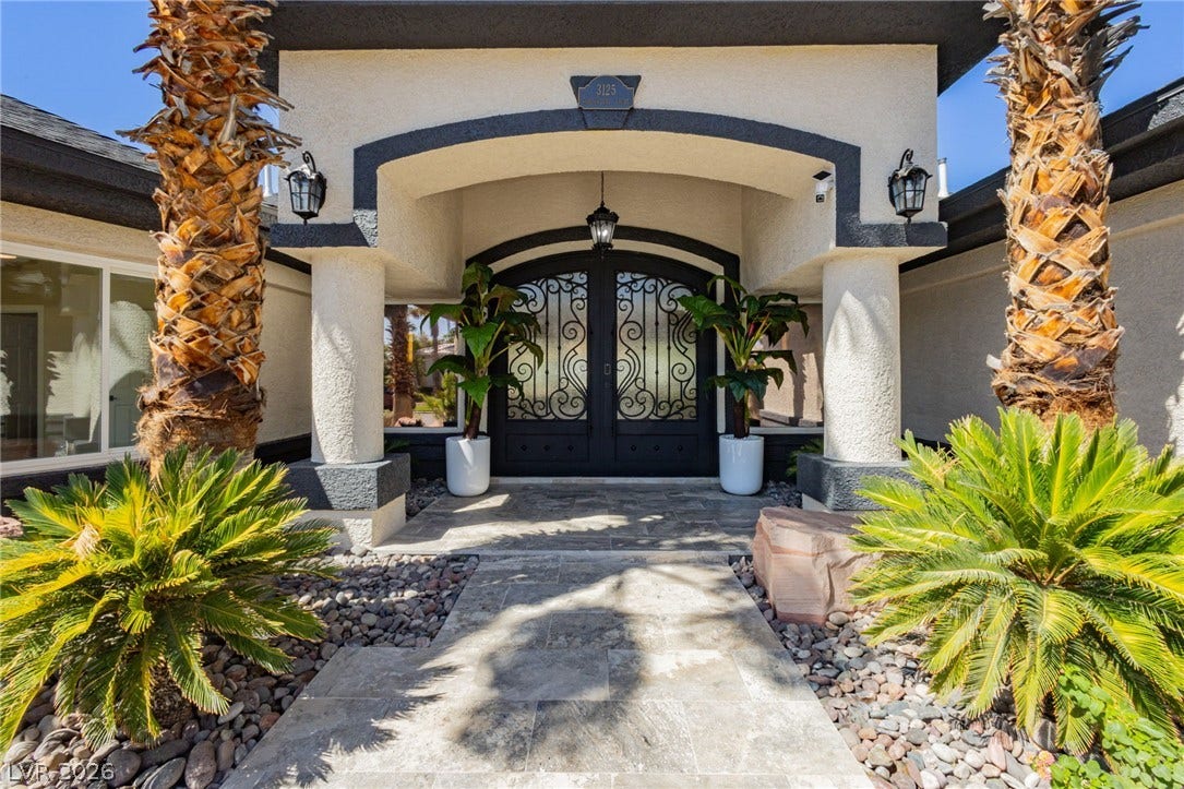 Double wrought iron doors create a stately entrance beneath a sheltered portico.