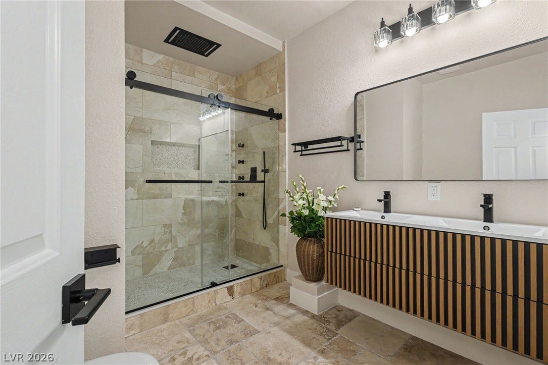A floating dual vanity and glass-enclosed walk-in tile shower define this modern space.