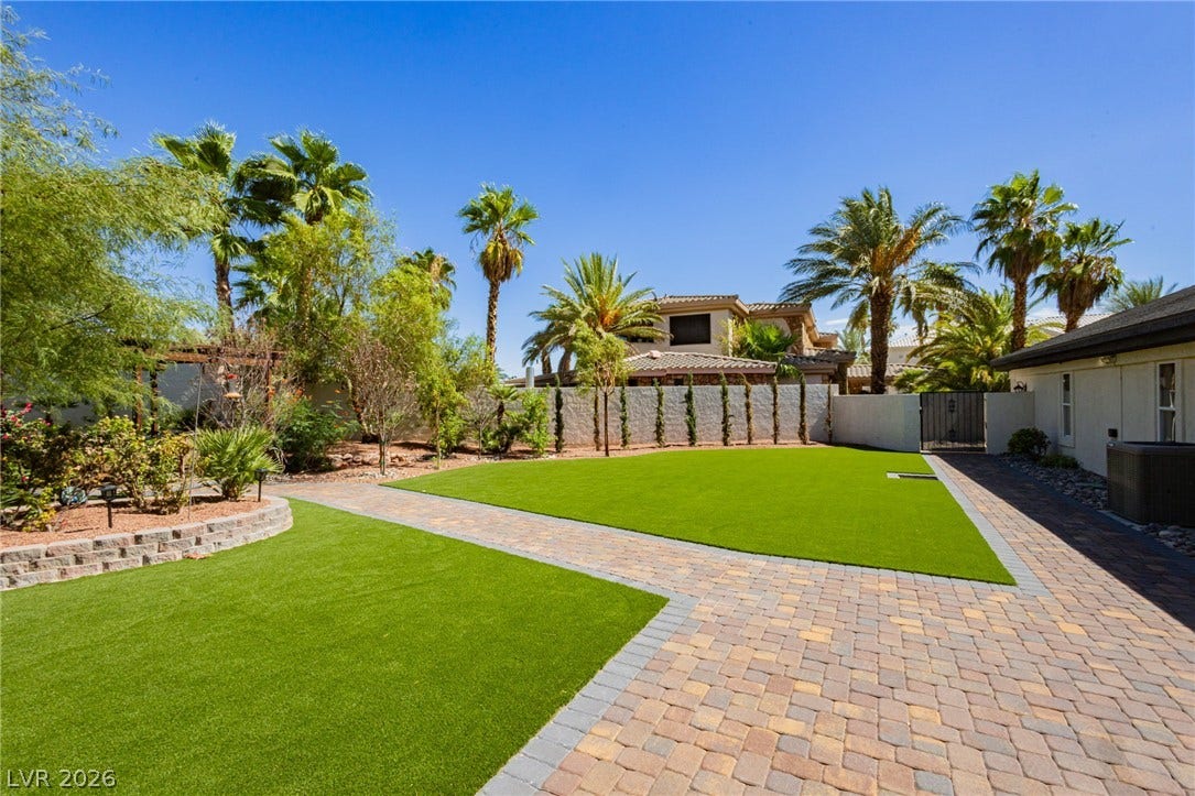 Manicured lawns and custom paver pathways frame a private, palm-lined retreat.