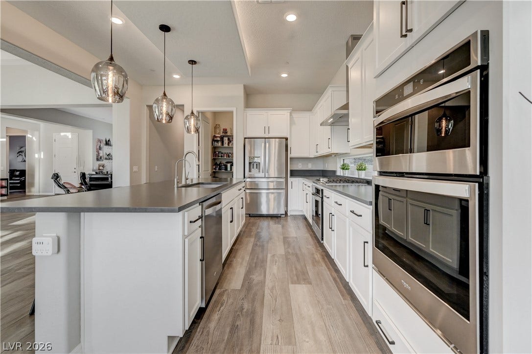 51 Thorn Creek Street, Henderson, NV 89011 Kitchen featuring stainless steel appliances, light wood-style floors, white cabinetry, a large island, and decorative light fixtures