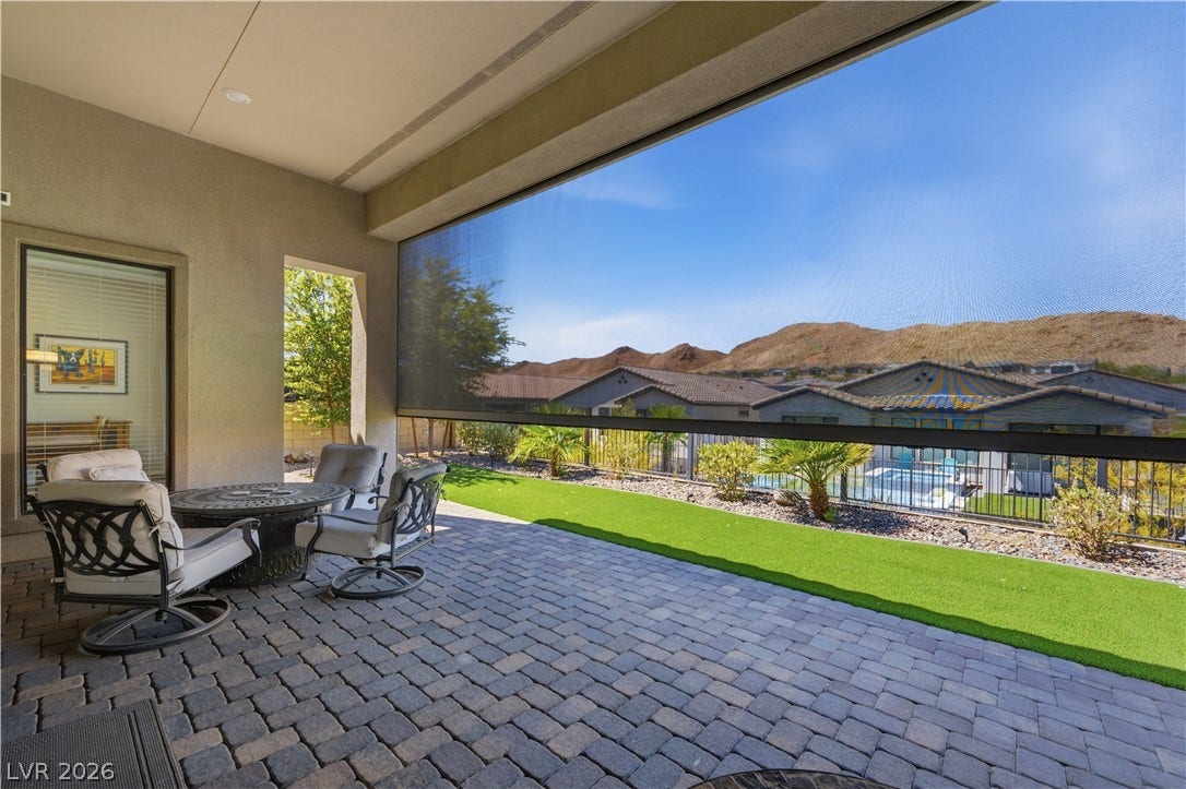 51 Thorn Creek Street, Henderson, NV 89011 An inviting covered patio featuring robust pavers looks out over a manicured lawn and mountain views.