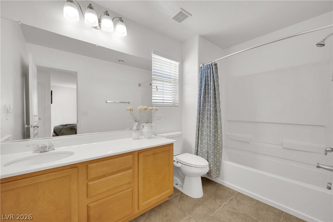 An integrated tub and shower combination sits alongside a spacious vanity in this well-appointed bathroom.