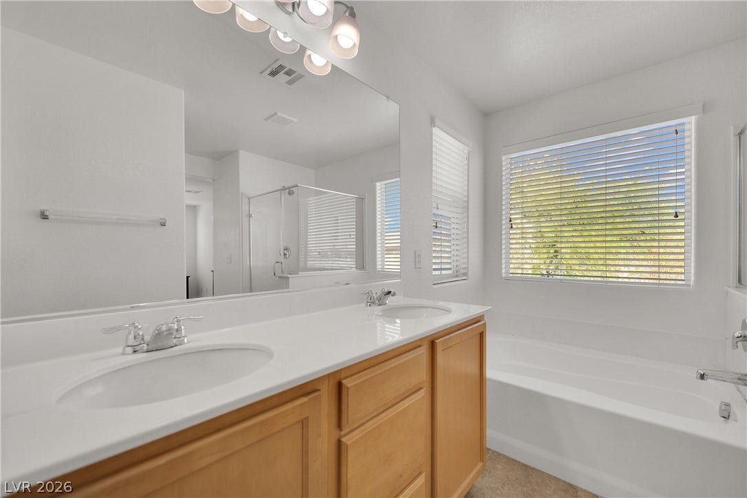Natural light washes over a modern dual-sink vanity and deep soaking tub.