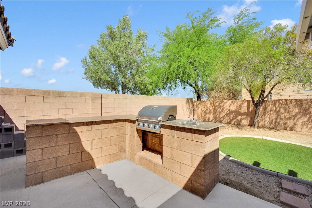 An outdoor kitchen with built-in barbecue grill and stone counters enhances the private yard.