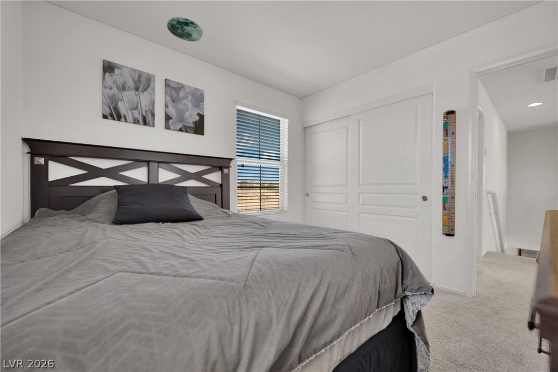 Plentiful natural light fills this serene bedroom featuring plush carpeting and a large closet.