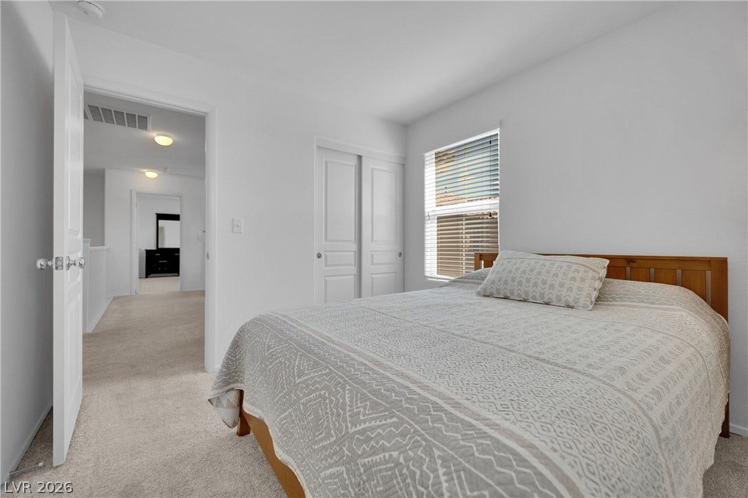 Plush carpeting and a large window create a serene environment in this peaceful bedroom.