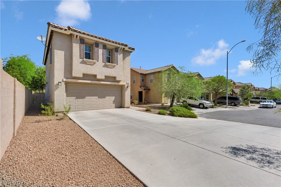 An expansive concrete driveway leads to a two-story residence with classic tile roofing.
