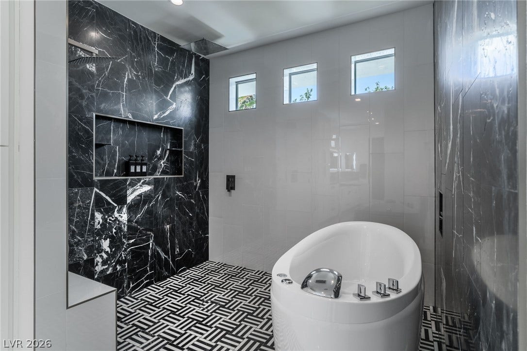 8633 Robinson Ridge Drive, Las Vegas, NV 89117 Dramatic dark marble tile walls and patterned flooring define this modern bathroom with a soaking tub.
