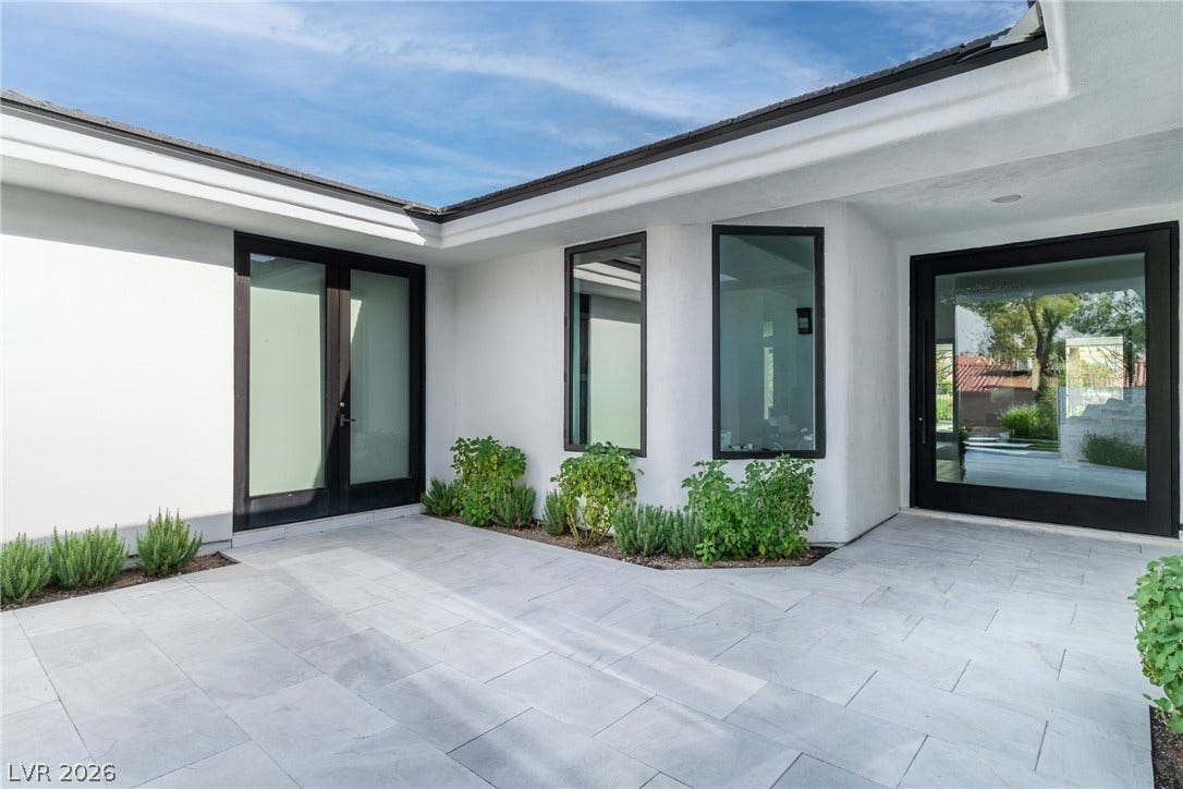 8633 Robinson Ridge Drive, Las Vegas, NV 89117 Smooth stucco walls and clean stone pavers frame this modern courtyard entrance under blue skies.
