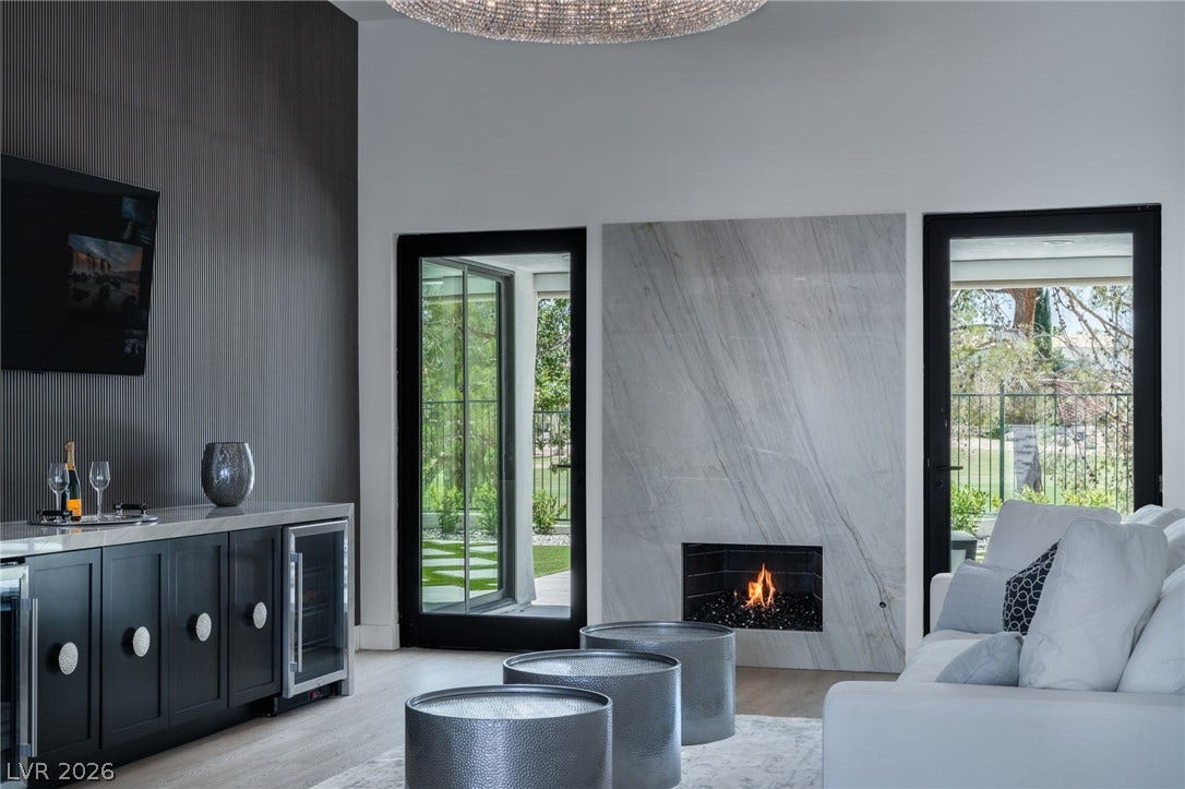 8633 Robinson Ridge Drive, Las Vegas, NV 89117 An elegant modern fireplace and custom built-in bar anchor this light-filled living area.
