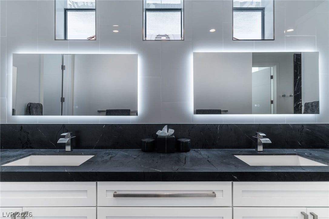 8633 Robinson Ridge Drive, Las Vegas, NV 89117 Clean modern vanity design with stone countertops and integrated under-mirror lighting.