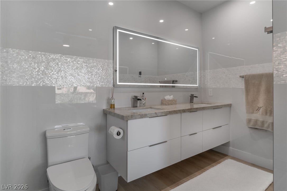 8633 Robinson Ridge Drive, Las Vegas, NV 89117 A floating double vanity and a backlit mirror anchor this modern primary bathroom.