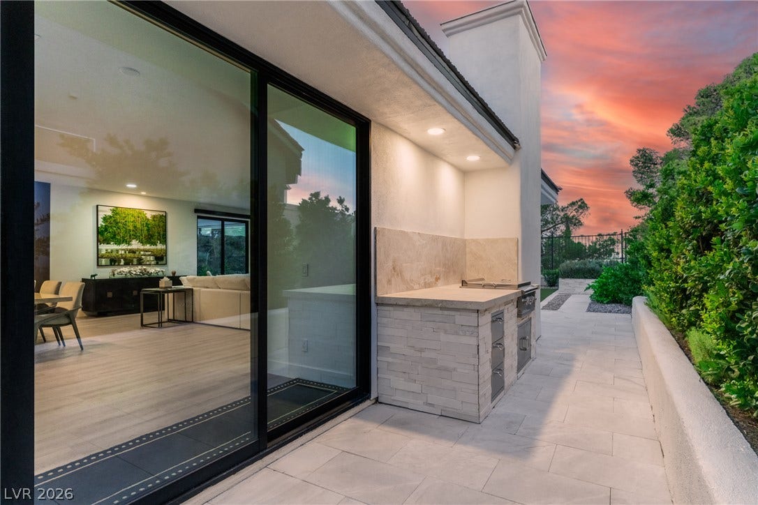 8633 Robinson Ridge Drive, Las Vegas, NV 89117 Sliding glass doors connect the open-concept interior to a stone-paved patio with an outdoor kitchen.