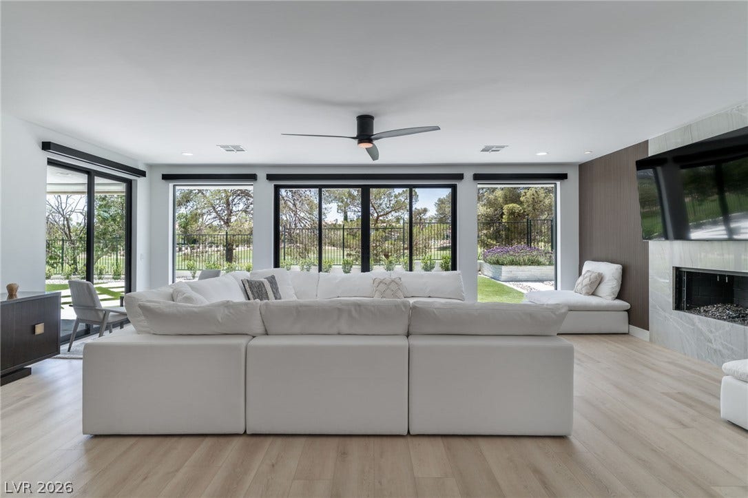 8633 Robinson Ridge Drive, Las Vegas, NV 89117 A spacious living room features elegant wood floors and expansive sliding glass doors opening to nature.