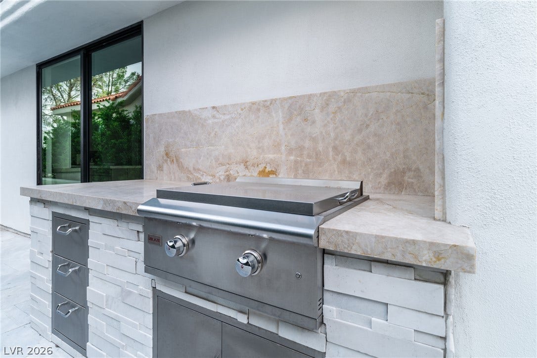 8633 Robinson Ridge Drive, Las Vegas, NV 89117 An outdoor kitchen features a built-in stainless steel grill set in stone counters.