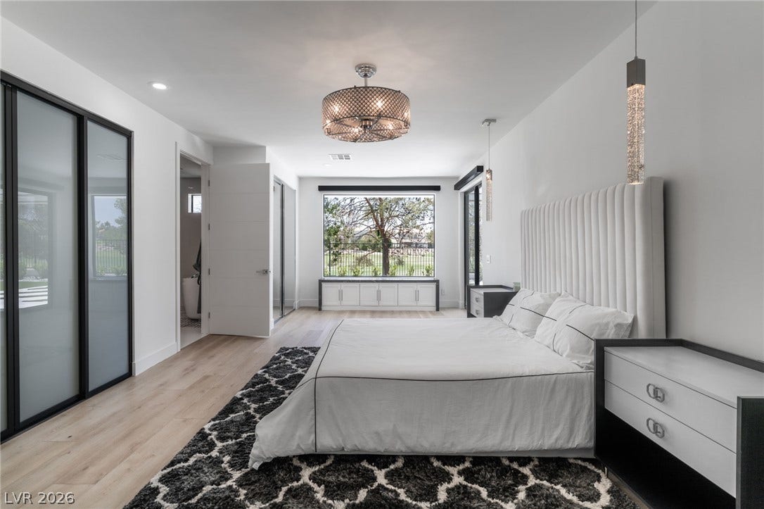 8633 Robinson Ridge Drive, Las Vegas, NV 89117 A spacious bedroom features modern light wood flooring and built-in window seating framing outdoor views.