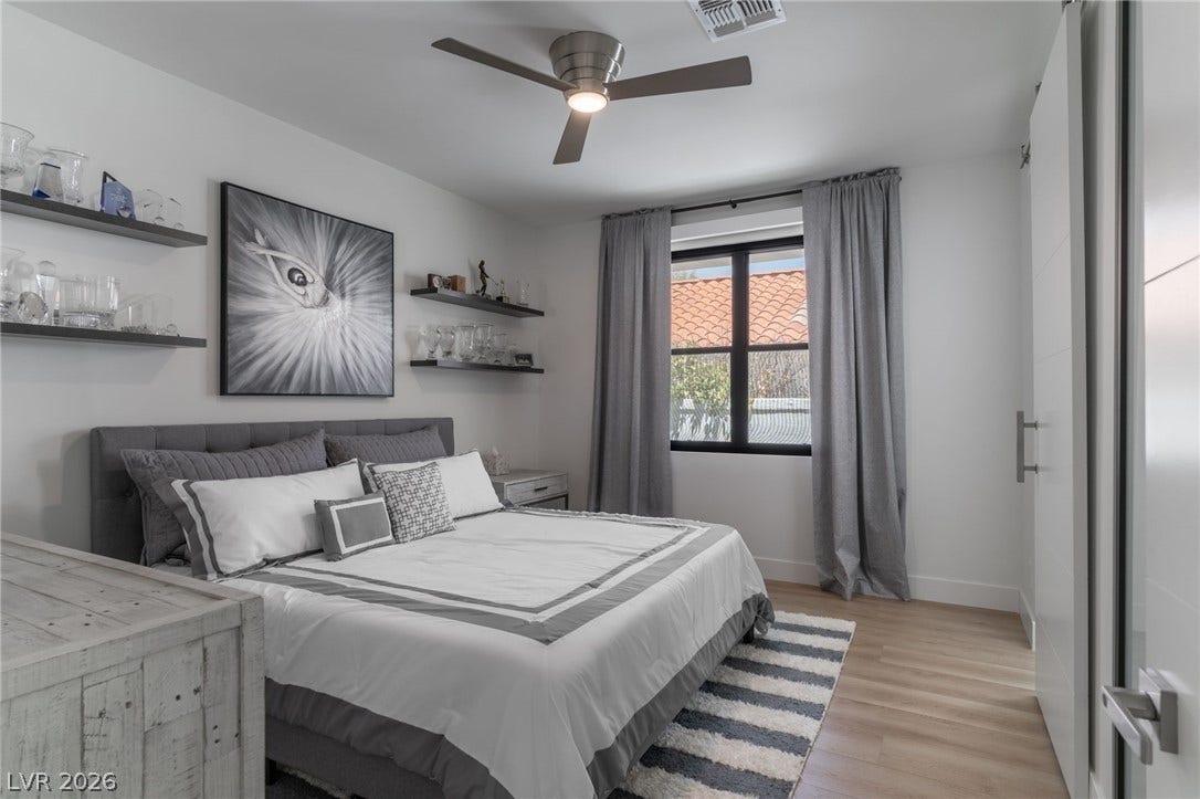 8633 Robinson Ridge Drive, Las Vegas, NV 89117 Smooth wood-style flooring and floating wall shelves define this comfortable bedroom space.