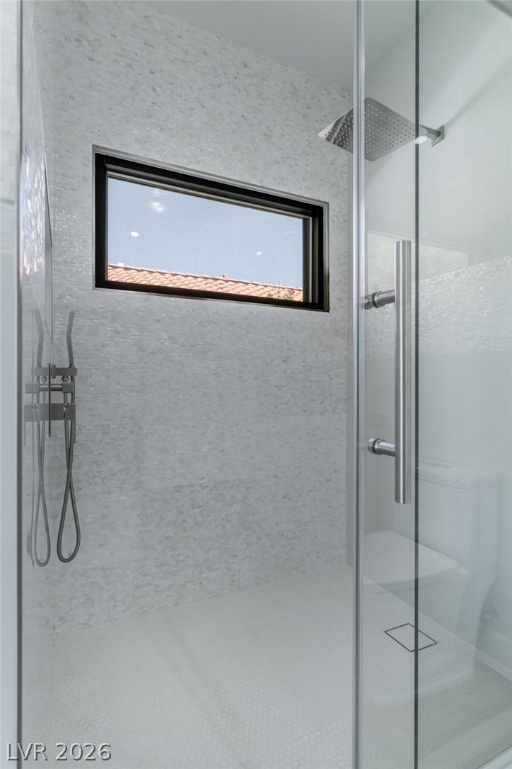 8633 Robinson Ridge Drive, Las Vegas, NV 89117 Tiled walls and a glass enclosure define this modern walk-in shower design.