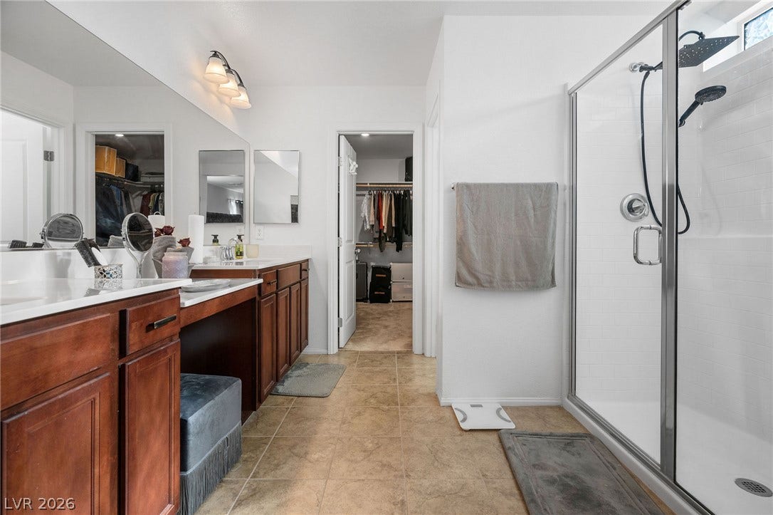 4605 Fragrant Street, North Las Vegas, NV 89031 Stone-look tile flooring spans a master bathroom featuring a glass-enclosed shower and dual-sink vanity.
