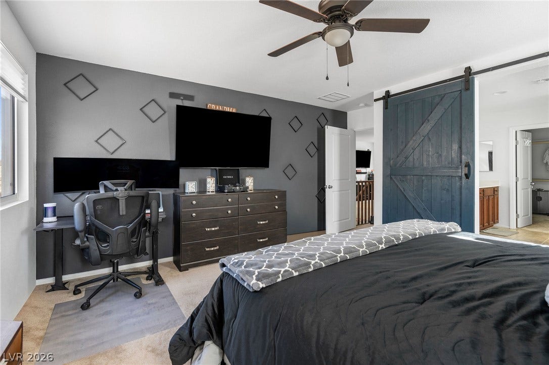 4605 Fragrant Street, North Las Vegas, NV 89031 A spacious bedroom features neutral carpeting and a rustic sliding barn door leading to the bath.