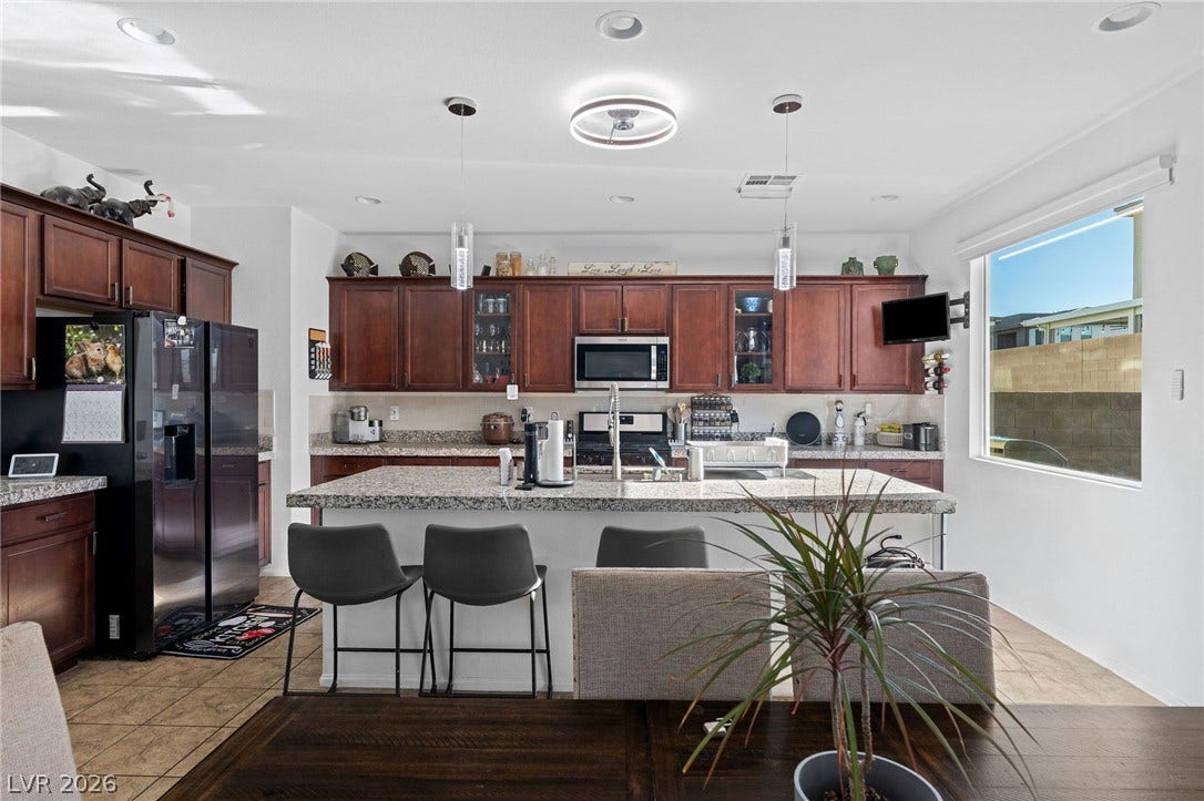 4605 Fragrant Street, North Las Vegas, NV 89031 A spacious central island sits beneath recessed lighting, surrounded by rich wood cabinets and tile flooring.