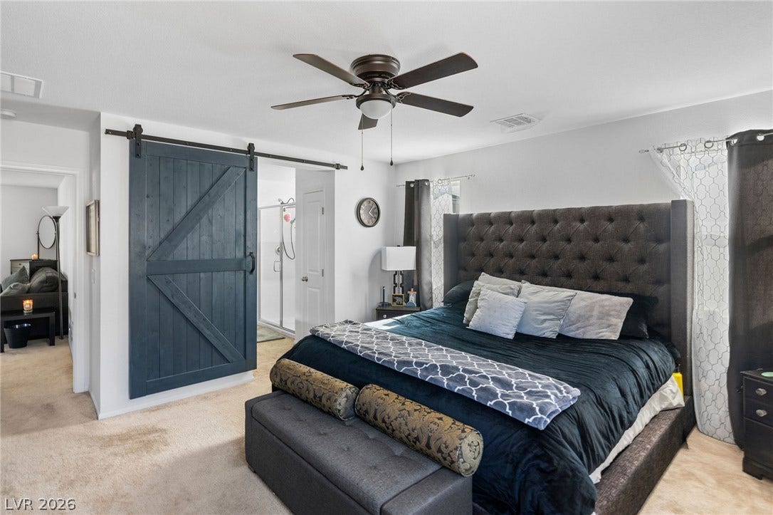 4605 Fragrant Street, North Las Vegas, NV 89031 A spacious bedroom showcases carpeted floors and a sliding barn door leading to the bathroom.