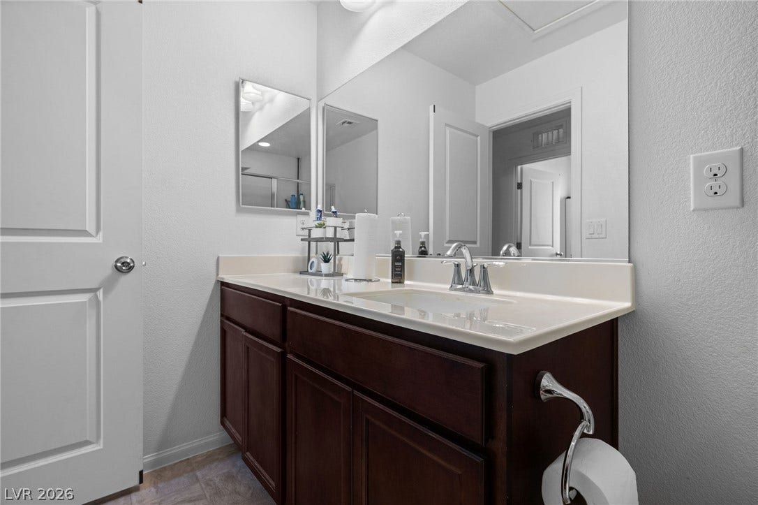 4605 Fragrant Street, North Las Vegas, NV 89031 Rich wood cabinetry anchors a classic washbasin counter beneath expansive mirrors.