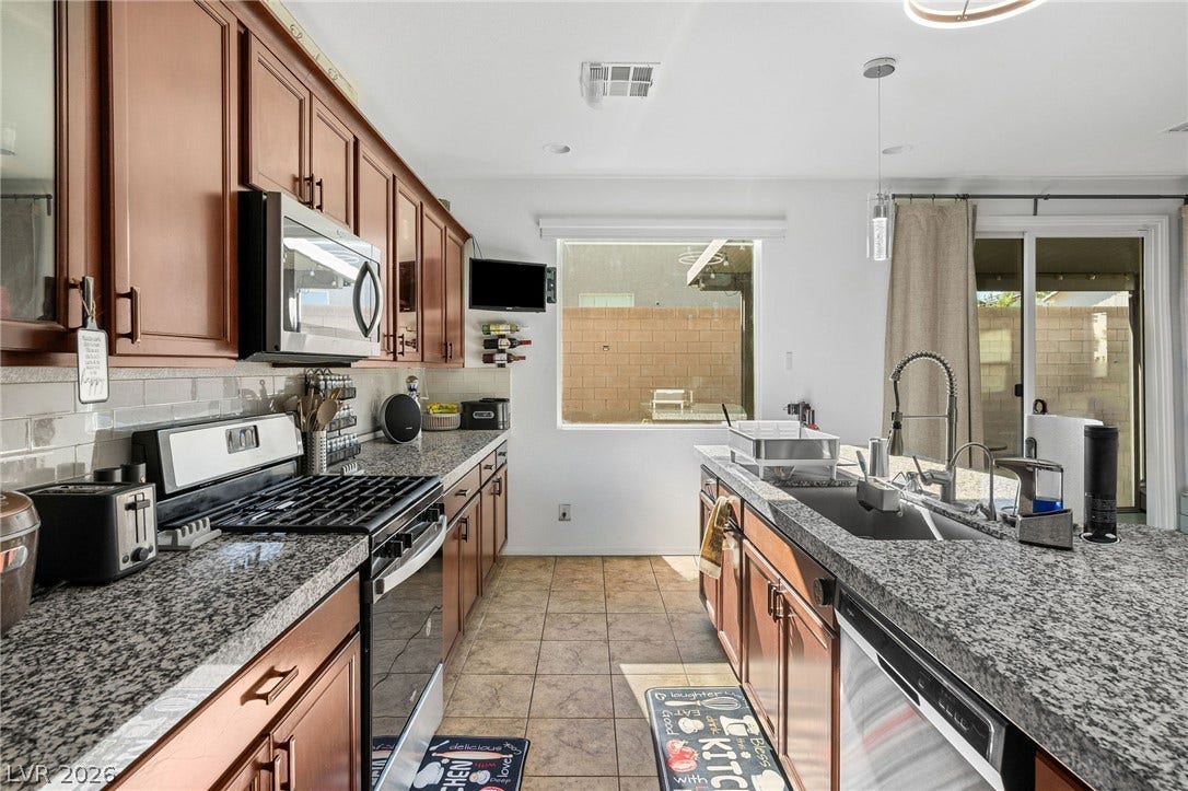 4605 Fragrant Street, North Las Vegas, NV 89031 Granite countertops and warm wood cabinetry define this functional workspace with a central island.