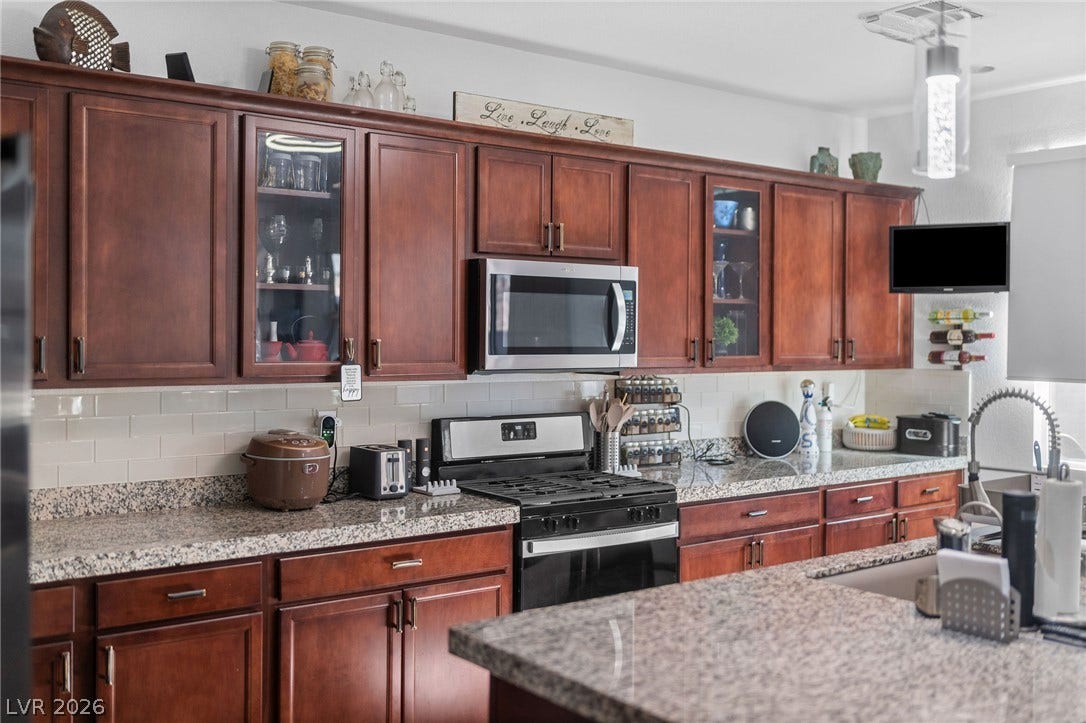 4605 Fragrant Street, North Las Vegas, NV 89031 Rich wood cabinetry paired with speckled stone countertops defines this workspace.