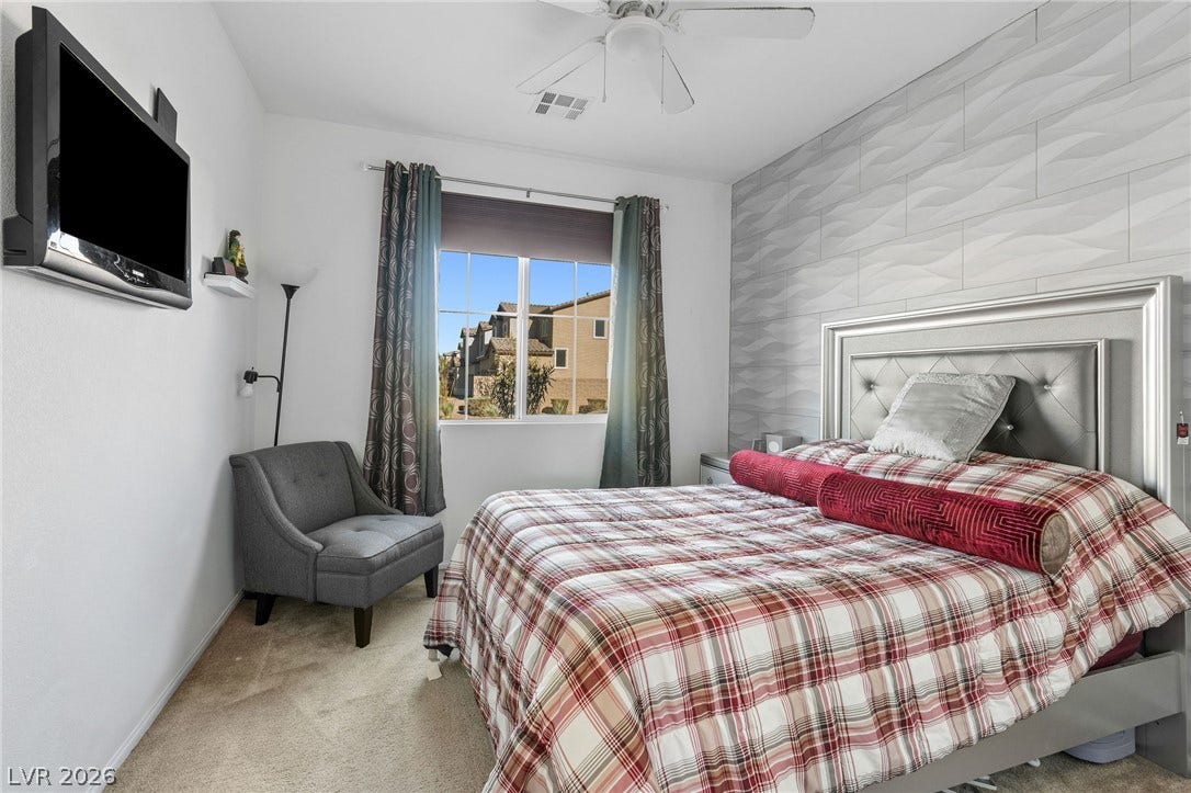4605 Fragrant Street, North Las Vegas, NV 89031 Downstairs bedroom, natural light streams through a large window highlighting textured wall details and plush carpeting.