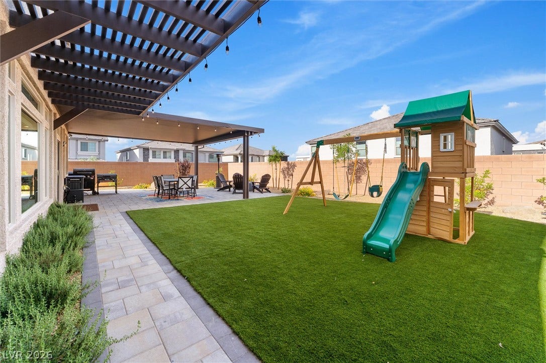 8724 Fortplaid Street, Las Vegas, NV 89139 An inviting backyard features a paved walkway, covered patio areas, and structured lawn spaces.