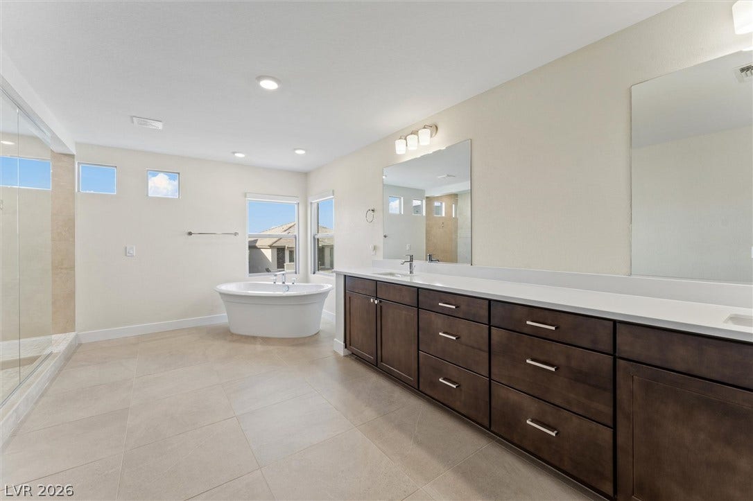 8724 Fortplaid Street, Las Vegas, NV 89139 An expansive vanity and a deep soaking tub anchor this modern bathroom space.