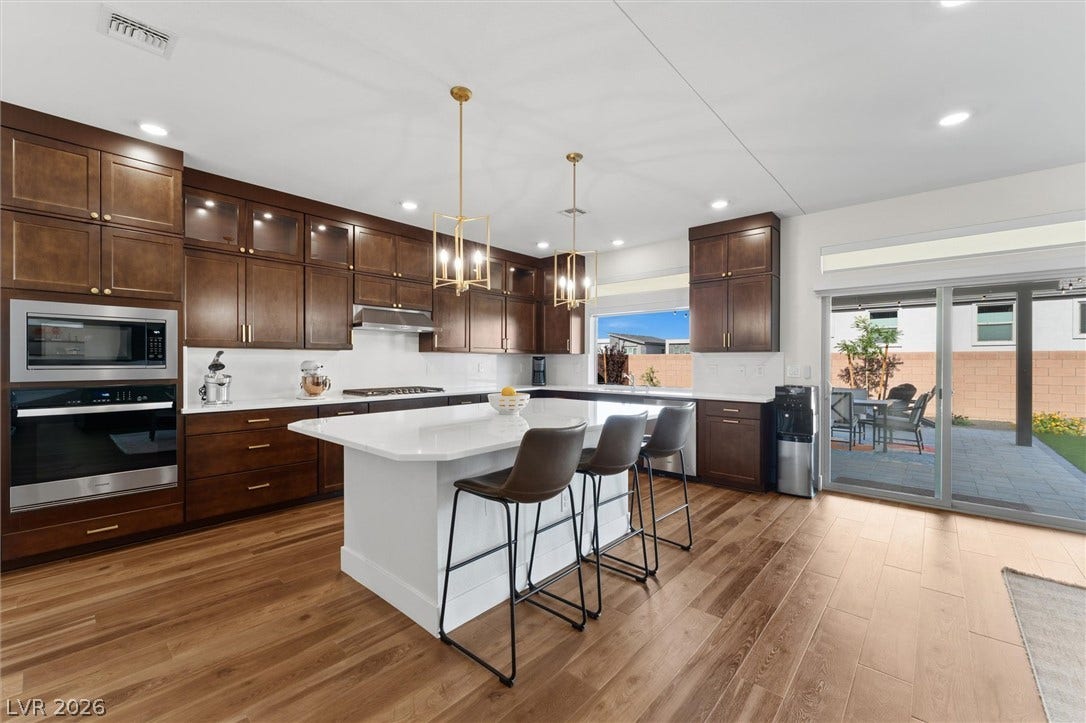 8724 Fortplaid Street, Las Vegas, NV 89139 Gleaming wood floors anchor this expansive kitchen featuring rich cabinetry and a central island.