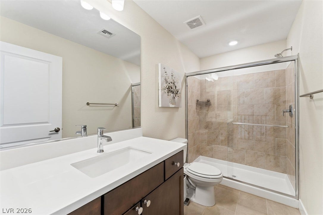 8724 Fortplaid Street, Las Vegas, NV 89139 Modern vanity features crisp solid surface counters alongside a tiled glass walk-in shower.