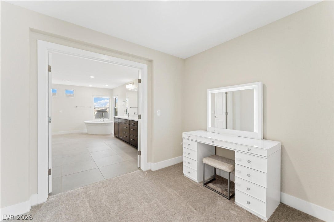 8724 Fortplaid Street, Las Vegas, NV 89139 An open doorway connects the carpeted dressing area to a spacious tile-floored bathroom.