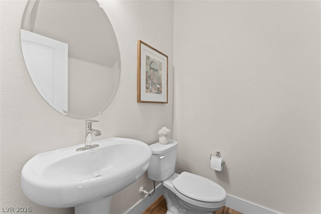 8724 Fortplaid Street, Las Vegas, NV 89139 A pedestal sink paired with a round mirror anchors this clean, modern powder room.