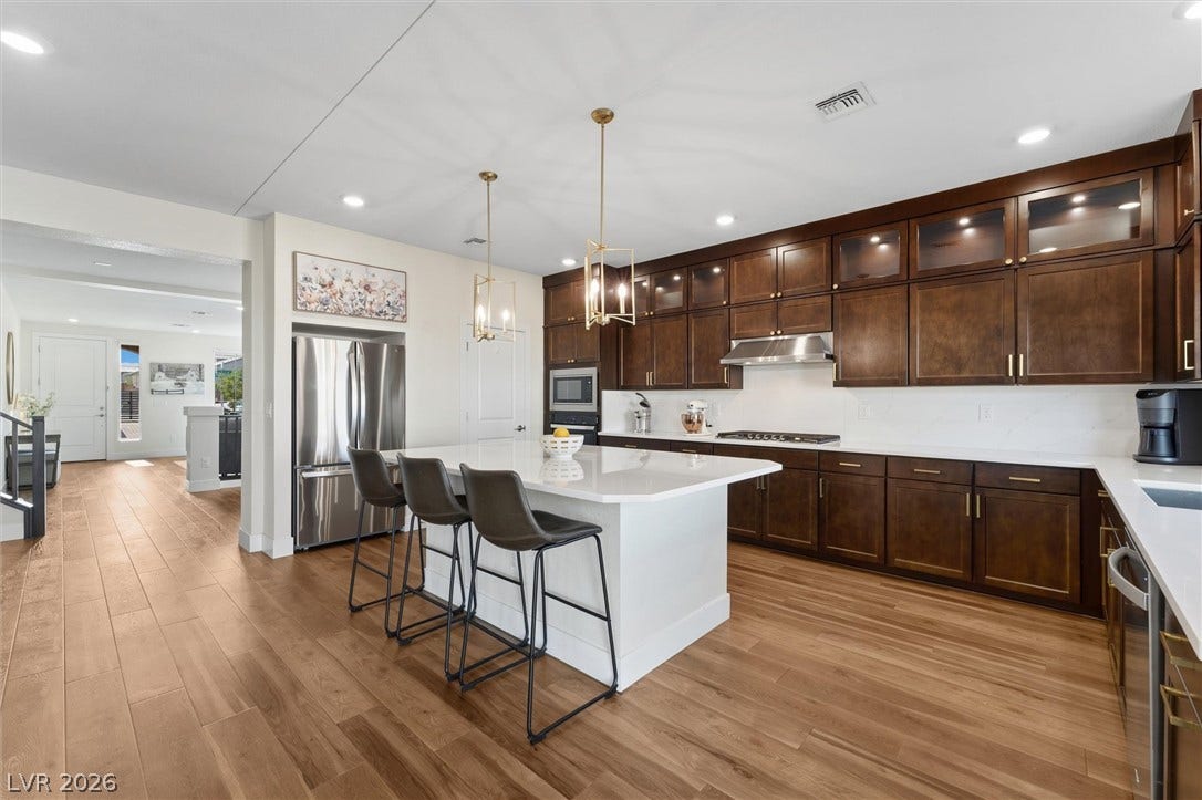 8724 Fortplaid Street, Las Vegas, NV 89139 Rich wood cabinetry contrasts beautifully with pristine stone countertops in this modern open kitchen.