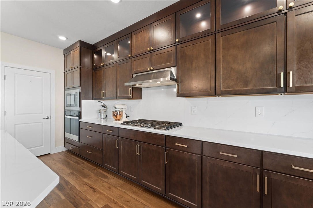 8724 Fortplaid Street, Las Vegas, NV 89139 Rich dark wood cabinetry pairs beautifully with light stone countertops and warm hardwood flooring.