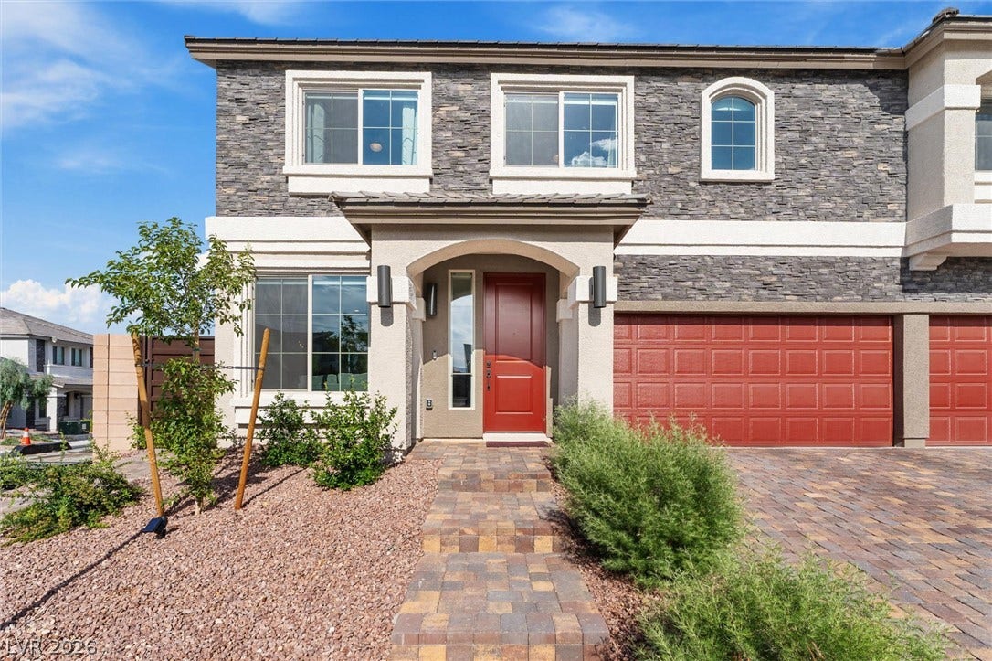 8724 Fortplaid Street, Las Vegas, NV 89139 Textured stone veneer, a bright entry door, and a paved walkway define this contemporary exterior.