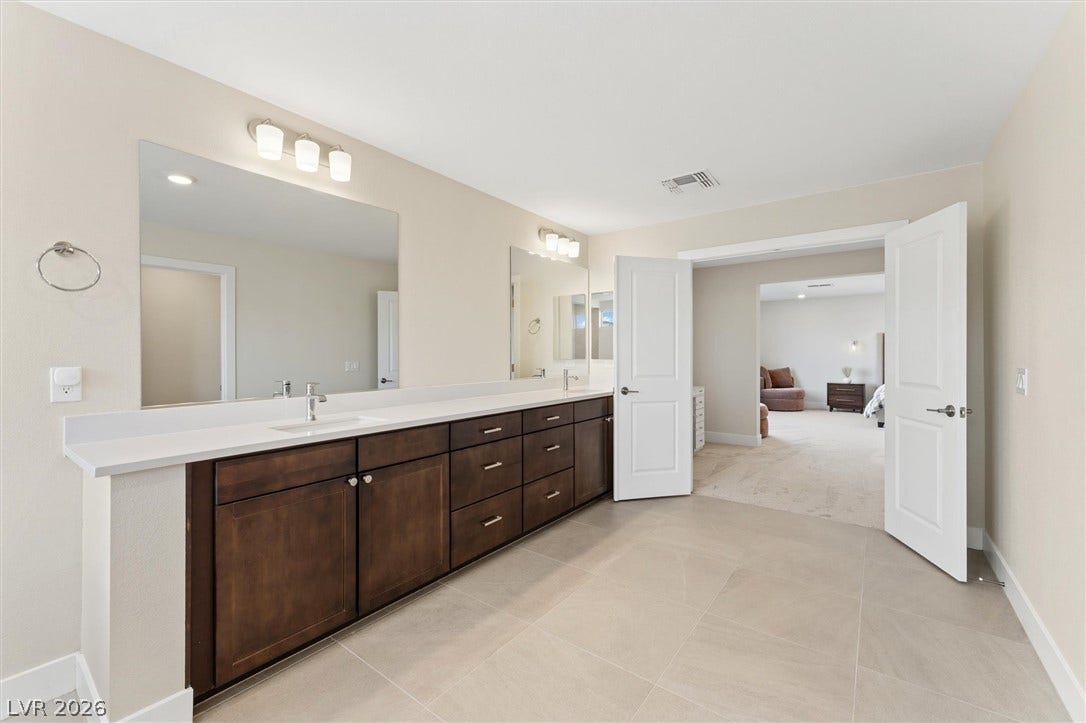 8724 Fortplaid Street, Las Vegas, NV 89139 Clean tile flooring and a lengthy dual vanity complete this spacious primary bathroom design.