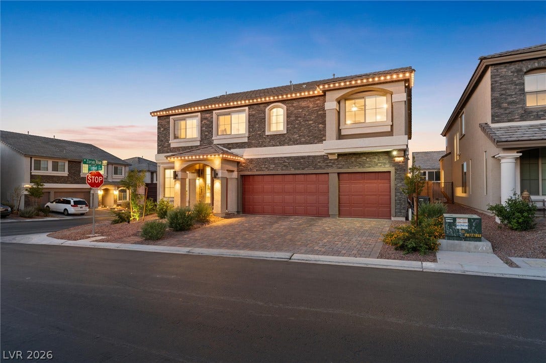 8724 Fortplaid Street, Las Vegas, NV 89139 Stone accents and a paved driveway elevate this two-story exterior at twilight.