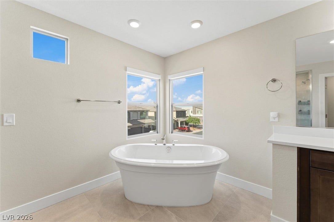 8724 Fortplaid Street, Las Vegas, NV 89139 An elegant freestanding soaking tub rests on tile flooring beneath recessed lighting.