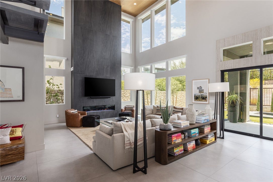 5216 Fading Sunset Drive, Las Vegas, NV 89135 A striking stone-clad fireplace anchors this generously proportioned living space, illuminated by an array of tall windows and glass sliding doors.